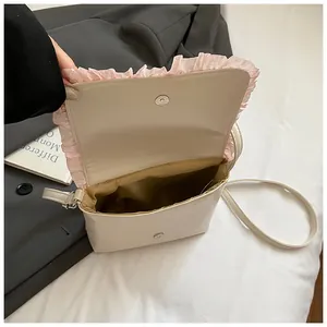 Detailed interior view of small white crossbody bag with pink ruffles and magnetic closure