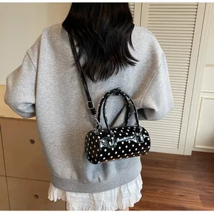 Rear view of a black polka dot cylindrical crossbody bag worn by a model in casual setting
