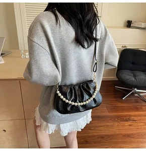 Detail der schwarzen Cloud Bag mit weißer Perlenkette und Lederriemen am Model