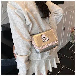 Detail of silver crossbody bag with pink lace trim and cute cartoon dog patch