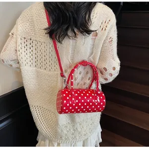 Detail of red polka dot pillow bag with leather handles and adjustable shoulder strap