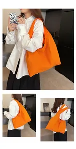 Detail view of large orange canvas tote bag with wide straps and textured fabric surface