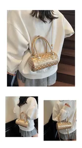 Detail of golden polka dot boston bag showing crossbody wear and double handle design