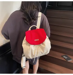 Detail of red drawstring closure on minimalist beige nylon backpack with brand patch