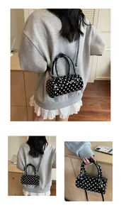 Close-up of a glossy black polka dot pillow bag with sturdy handles and adjustable strap
