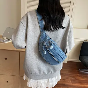 Detailed back view of a blue denim crescent crossbody bag on a model in a casual setting
