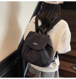 Rear view of black drawstring backpack with flap and brand plaque on a casual model