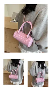 Detail showing pink polka dot cylinder handbag with top handles and shoulder strap