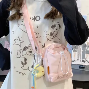 Detail van roze nylon crossbodytas met trekkoordsluiting en gele maanbedel