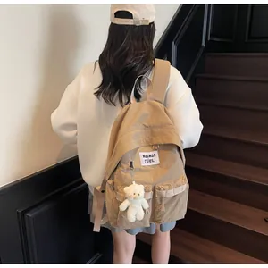 Detail of khaki canvas backpack with symmetrical pockets and cute white bear keychain