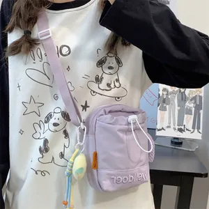Detail van lichtpaarse canvas crossbodytas met Welldoer-borduurwerk en trekkoordsluiting