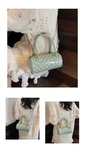 Detail of light green polka dot barrel bag with glossy finish and adjustable strap