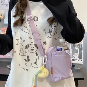 Detail van paarse nylon crossbodytas met trekkoordsluiting en pluchen vogelhanger