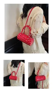 Detailed macro view of red glossy polka dot barrel bag with metal zipper and strap