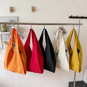 Minimalist canvas tote bags in five colors hanging on a rack for daily fashion use