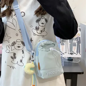 Minimalistische lichtmintblauwe crossbodytas met trekkoord en gele pluchen hanger