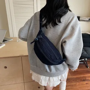 Deep blue denim half-moon shoulder bag with zipper detail on a casual lifestyle background