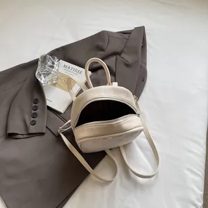 Mini mochila de moda en color crema de cuero sintético sobre una elegante chaqueta de traje