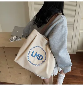 Close-up of elegant blue circular embroidery and leather strap on canvas tote bag