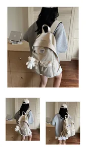 Detail view of cream canvas backpack with cute bear pendant and multiple buckled pockets