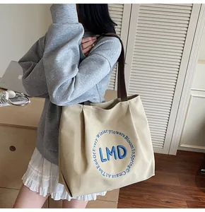 Detailed view of the blue floral embroidery and LMD text on the beige canvas tote bag