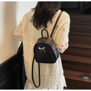 Detalle de mini mochila negra con mariposa metálica y perlas para mujer con estilo