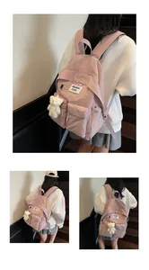 Detail of pink nylon backpack featuring a plush bear charm and Waswac rules patch