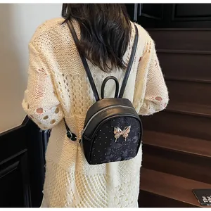 Detalle de mini mochila negra con cierre de mariposa dorada y lunares blancos