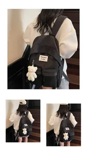 Minimalist black student backpack detail with stylish plush bear pendant and logo label