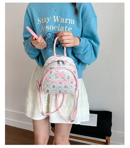Detailed close-up of mini white and pink backpack with cartoon bear patterns and dual straps
