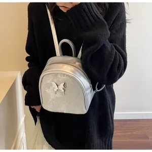 Primer plano de una mini mochila plateada con acabado metálico y cierre de mariposa