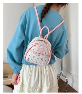 Close-up of pink mini backpack with bear patterns and faux leather straps on a model