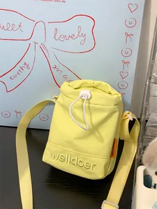 Detailopname van lichtgele nylon crossbodytas met borduursel en trekkoordsluiting