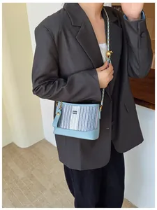 Détail du sac seau à rayures bleues avec bandoulière chaîne et fermoir boule dorée