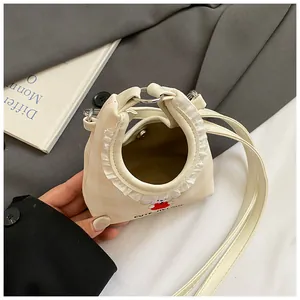 Dettaglio mini borsa a secchiello crema con pizzo e ricamo a forma di coniglietto