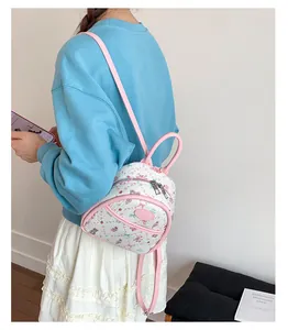 Detailed back view of a mini white floral backpack with pink straps on a female model