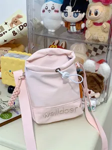 Detail van roze bucket bag met trekkoord, welldoer borduursel en een geweven riem