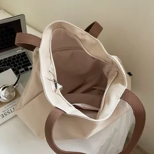 Minimalist beige canvas tote bag with brown straps and zipper closure for daily commute