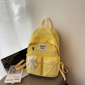 Minimalist bright yellow nylon backpack with cute bear pendant and laptop essentials