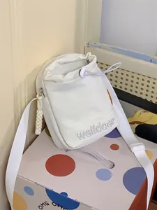Detail van witte canvas crossbody tas met welldoer borduursel en vak met ritssluiting