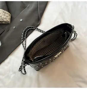 Close-up of quilted black bag with silver studs and striped inner lining detail