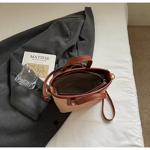 Detailansicht einer gewebten Strohhandtasche mit braunen Ledergriffen und Reißverschluss