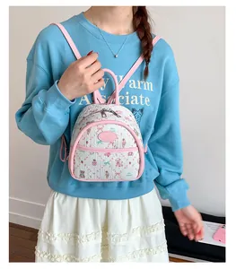 Mini pink white backpack with cute cartoon prints shown on a model in a casual setting