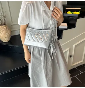 Detail of silver quilted crossbody bag with metal star accent and tassel on chain strap