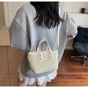 Detail der cremefarbenen Web-Tasche mit Lederbesatz und Goldnieten am Model