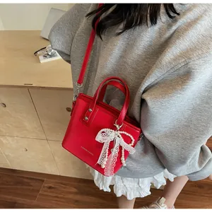 Detail of red small bucket bag with lace bow, pearl pendant and fashion lettering