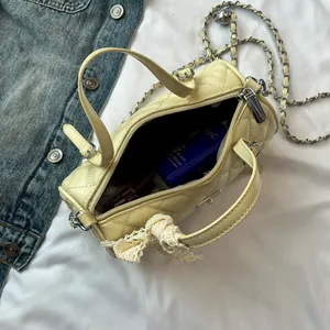 Sac cylindrique matelassé jaune avec bandoulière chaîne et nœud en dentelle