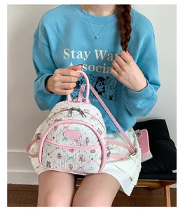 Close-up of a mini white backpack with pink trim and cute bear strawberry prints