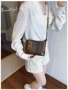 Détail du sac seau matelassé avec bandoulière chaîne et breloque dorée élégante