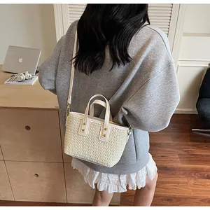 Detail der beigen geflochtenen Tasche mit feiner Strohtextur und goldener Hardware